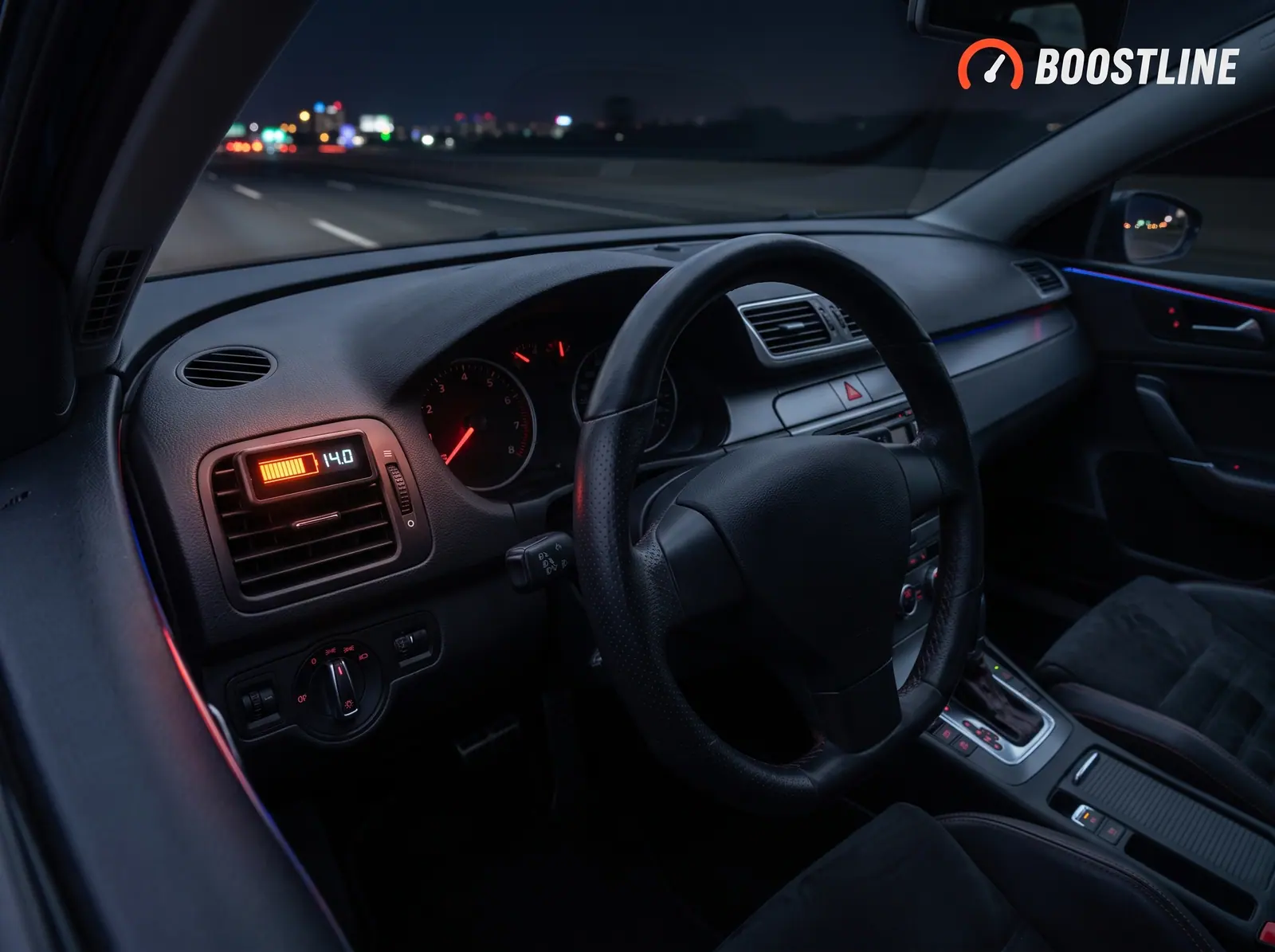 Interior de un coche de noche con un indicador digital integrado en la rejilla de ventilación que marca 14,0 voltios